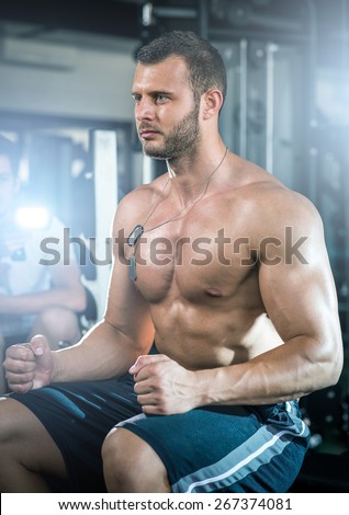 Young adult man sitting in gym and preparing for workout