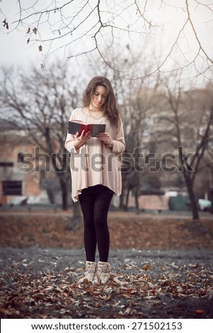 Young adult girl reading a book in park wearing nice blouse