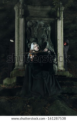 Dark lady is playing a fiddle in a graveyard. Mysterious spirit are attracted by the music
