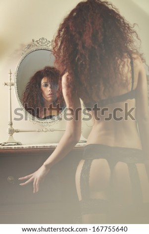 Mirror reflection of a beautiful woman in lingerie . Focus on the face