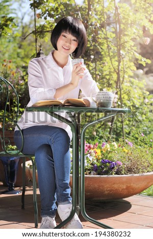 Summer portrait of a beautiful girl relaxing with a book and tea