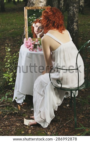 Red hair woman mirror reflection in a forest. Surreal and vintage