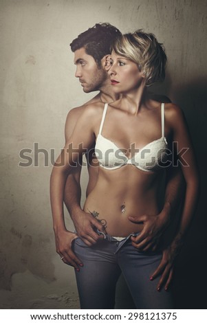 Beautiful fashion couple posing shirtless against old wall . Urban style