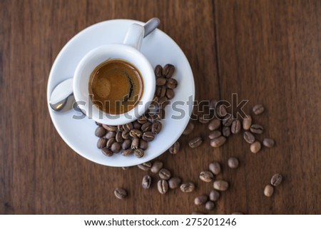 Coffee with a smile of cream and roasted beans in a white porcelain cup