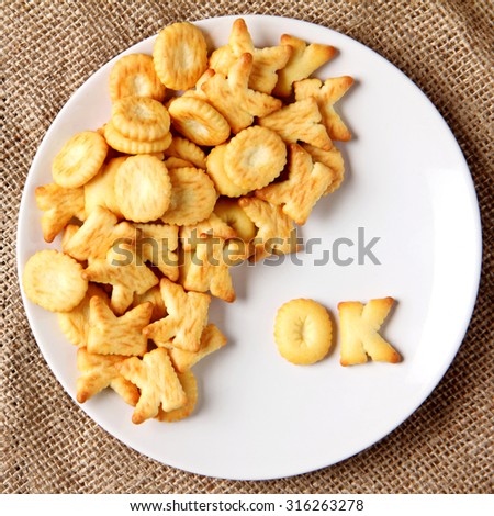 alphabet cracker word  ok in white dish on burlap cloth background