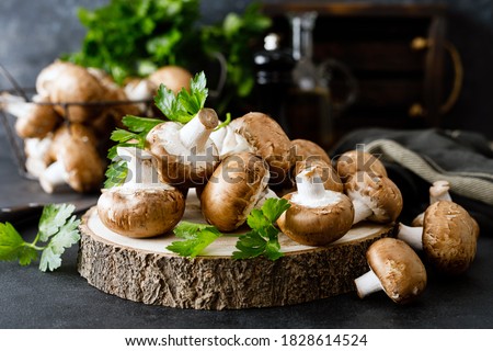 Raw mushrooms champignons on black background, cooking fresh champignons