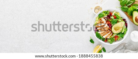 Grilled chicken meat and fresh vegetable salad of tomato, avocado, lettuce and spinach. Healthy and detox food concept. Ketogenic diet. Buddha bowl dish on white background, top view. Banner.