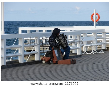 Man playing accordion on the pier and trying to earn money for a food