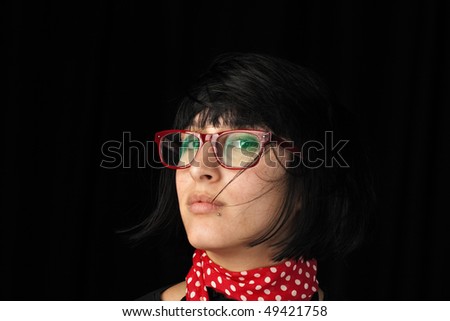 A fashion retro looking young female, wearing red glasses and a red polka dots scarf, gazing at you, with messy hair