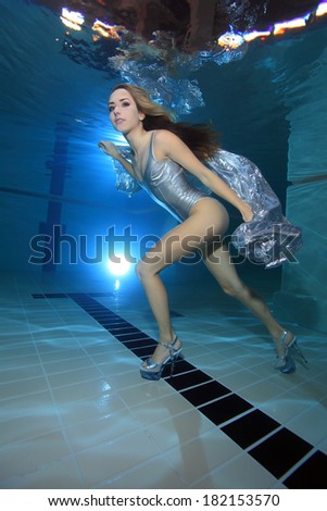 Underwater model with silver swimsuit and high heels underwater in the pool