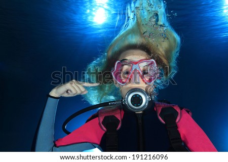 Female scuba diver show the underwater sign for ear problems