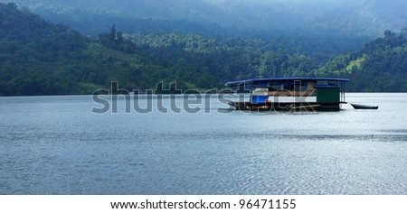 Boat house sailing at Kenyir Lake in Terengganu Malaysia with tropical rain forest in the background