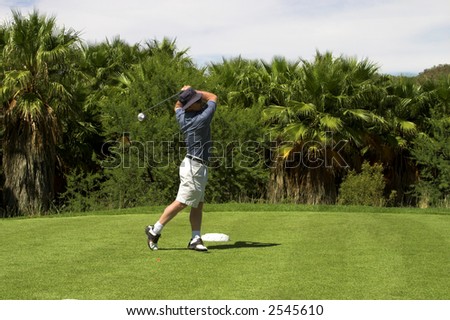 Golfer hitting the ball from the tee box. Golf club is slightly in motion.