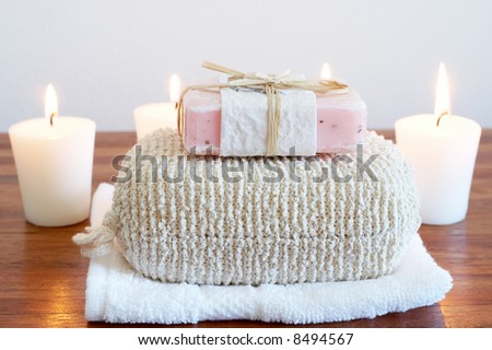 Relaxing spa scene with sponge, handmade soap, white towel and candles in the background