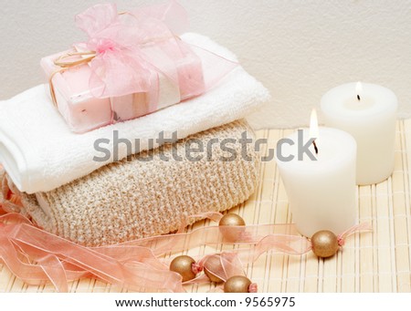 Relaxing spa scene with exfoliating body sponge, face towel, handmade soap and candles