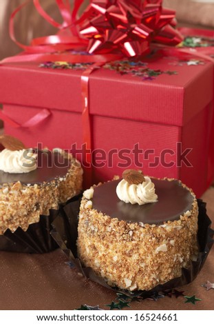 Miniature chocolate meringue cakes with cream and almonds and red gift boxes in the background