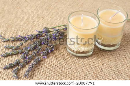 Relaxing spa scene with a purple lavender and beautiful handmade candles on brown mesh material