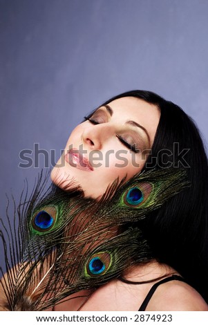 Beautiful young woman with peacock\'s feathers