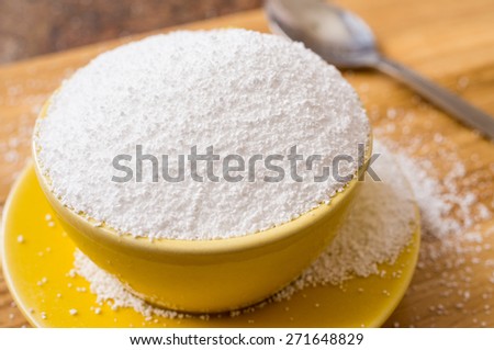 Cup of sorbitol, a natural sweetener on the table next to a spoon. Closeup