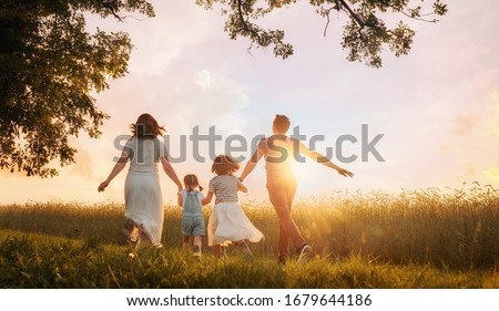 Happy family on summer walk! Mother, father and daughters walking in the Park and enjoying the beautiful nature.