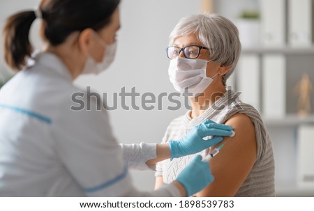 Doctor giving a senior woman a vaccination. Virus protection. COVID-2019.