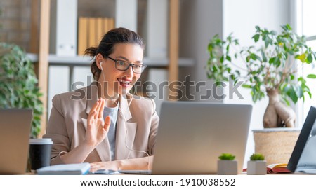 Photo of Happy casual beautiful woman working on a laptop, talking with somebody in office.