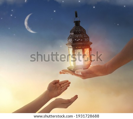 Ornamental Arabic lantern with burning candle glowing in hand. Festive greeting card, invitation for Muslim holy month Ramadan Kareem.