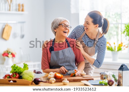 Happy family in the kitchen. Mother and her adult daughter are preparing proper meal. 
