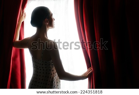 pretty woman opening red curtains