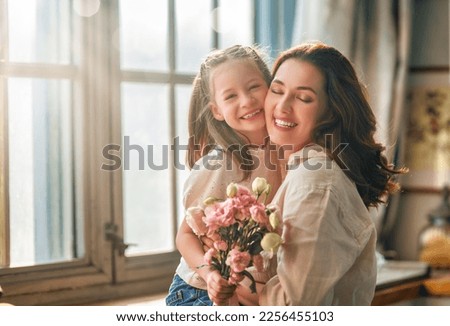 Similar – Image, Stock Photo Child daughter congratulates mother and gives present card, gift and bouquet of flowers at home. Mom and girl smiling and hugging on couch. Happy mothers day celebration