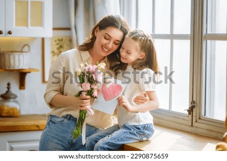 Image, Stock Photo Child daughter congratulates mother and gives present card, gift and bouquet of flowers at home. Mom and girl smiling and hugging on couch. Happy mothers day celebration