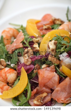 Fresh mixed salad with nuts, shrimps, salmon and peaches close up