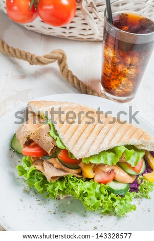 Kebab in grilled pita bread next to cold beverage