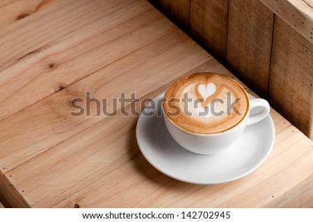 double heart shaped latte art in white ceramic cup on wooden background