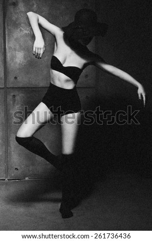 Attractive sexy young woman with perfect body posing on the gray background. Black-and-white photo.