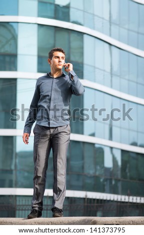 Street portrait of the youth talking on a cell phone in front of the office building