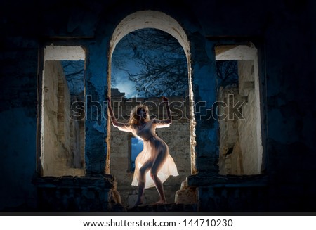 Mysterious female figure standing in the arc of the ruined building