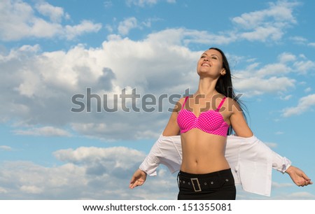 Smiling business lady unbuttoning her white shirt and revealing a pink bikini, outdoors portrait