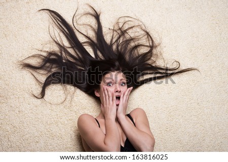 Portrait of a scared girl with long hair lying on the floor, view from above