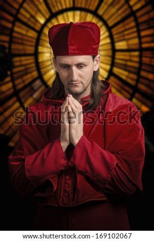 Antique style portrait of a praying man in historical medieval cardinal\'s vestments