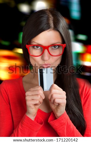 Portrait of a woman in red frame glasses with a plastic card, city lights background