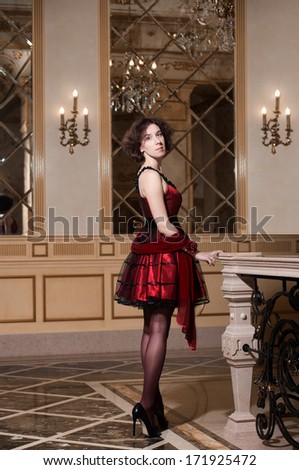 Full-length portrait of a woman in red cocktail dress in luxury interior