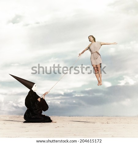Woman flying like a kite driven by the mysterious person dressed in the black cloak