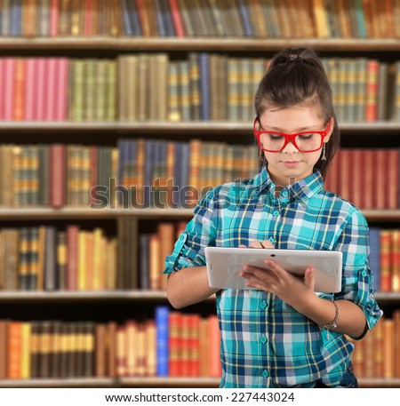 Preteen girl looking at a Pad Tablet PC screen, library background