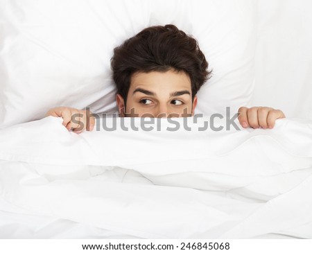 Man hiding in bed under the sheets