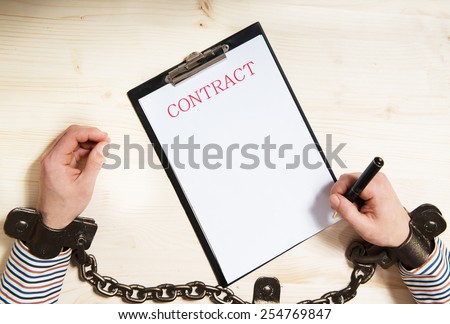 Chained hand signing a contract, concept