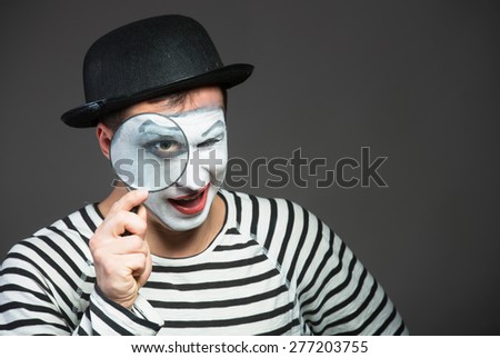 Male mime looking through the magnifying glass