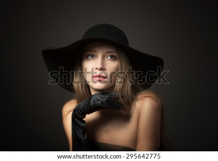 Blond lady in big black hat, studio portrait