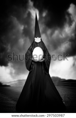 Strange person in black cloak with an egg