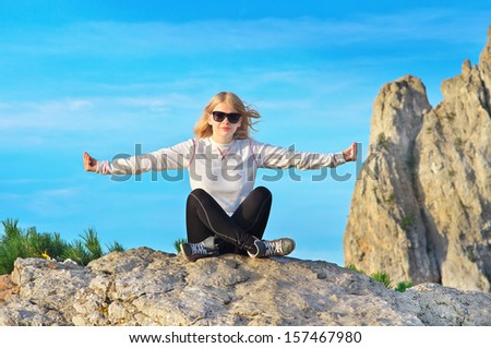 Woman Traveler Relaxing Yoga Meditation sitting on stones relaxing with Rocky Mountain peak Ai-Petri and blue sky on Background